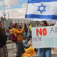 ISRAELI DEMONSTRATORS GATHER BY THE BORDER FENCE WITH EGYPT AT THE NITZANA BORDER CROSSING IN SOUTHERN ISRAEL ON FEBRUARY 18, 2024, AS THEY ATTEMPT TO BLOCK HUMANITARIAN AID TRUCKS FROM ENTERING INTO ISRAEL ON THEIR WAY TO THE GAZA STRIP. (PHOTO: GIL COHEN-MAGEN/AFP VIA GETTY IMAGES)